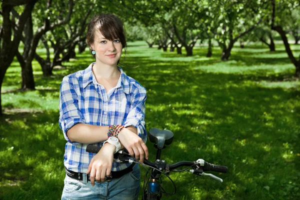 stock image A young girl with a bicycle in the park