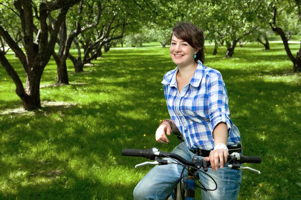 A young girl with a bicycle in the park — Stock Photo, Image