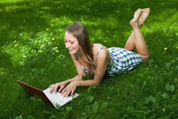 Chica atractiva con un ordenador portátil en el parque —  Fotos de Stock