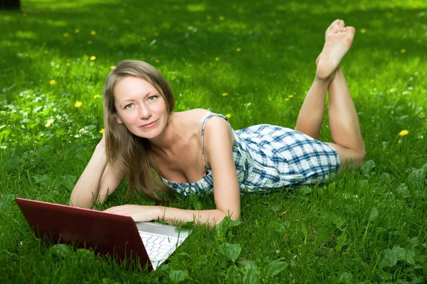 Attractive girl with a laptop in the park — Stock Photo, Image