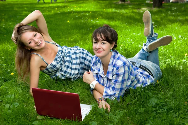 Twee mooie meisjes met een laptop in het park — Stockfoto
