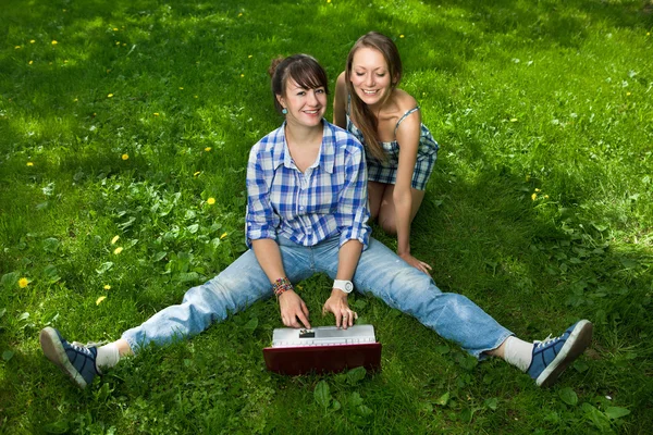 Duas meninas atraentes com um laptop no parque — Fotografia de Stock