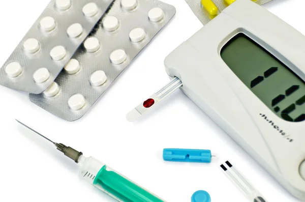 Glucometer with pills and a syringe — Stock Photo, Image