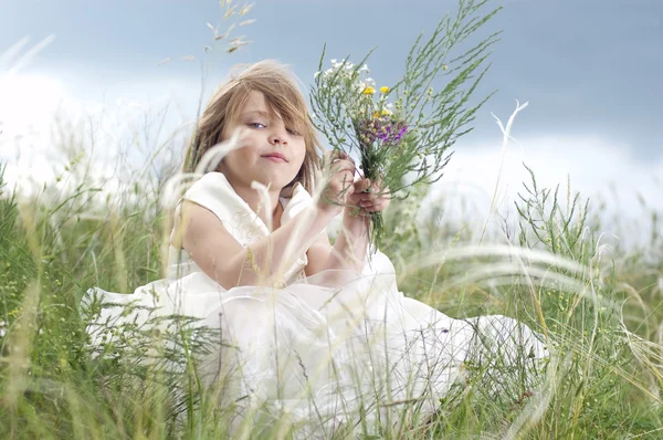 Казкова красива дівчинка на газоні з польовою квіткою — стокове фото