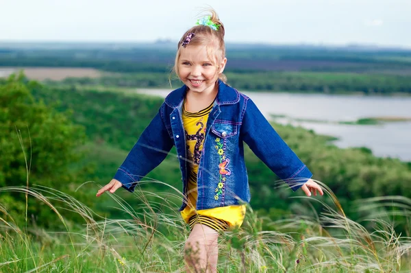 Красивая маленькая девочка в джинсовой одежде на прогулке под открытым небом — стоковое фото