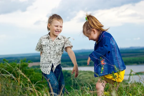 Una niña y un niño juegan y aplauden un paseo al aire libre — Foto de Stock