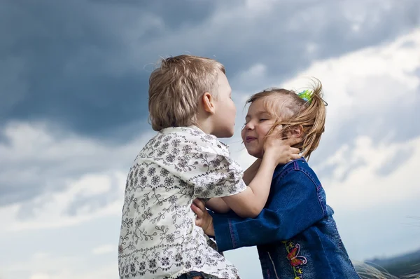 Маленький мальчик и девочка целуются на заднем плане пейзаж — стоковое фото