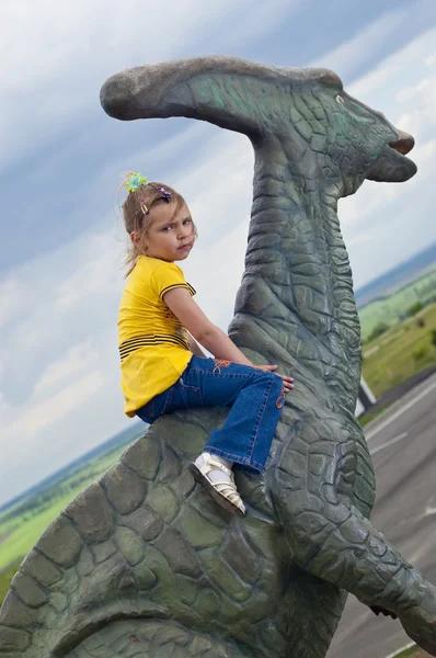 Moedig meisje op een dinosaurus in een park — Stockfoto