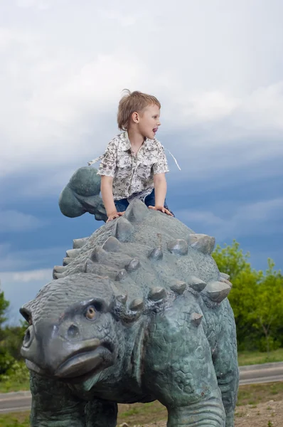 Petit garçon courageux sur un dinosaure dans un parc — Photo
