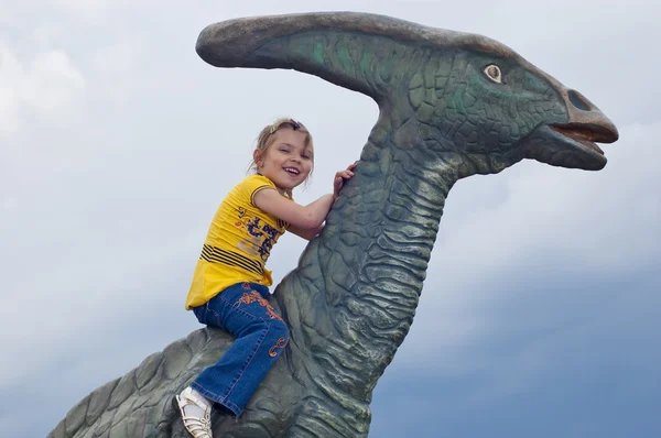 Little brave girl on a dinosaur in a park — Stock Photo, Image