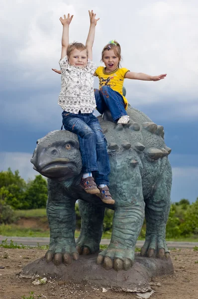 Kleine tapfere Kinder auf einem Dinosaurier im Park — Stockfoto