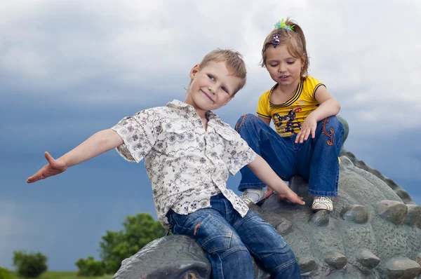 Piccoli bambini coraggiosi su un dinosauro in un parco — Foto Stock