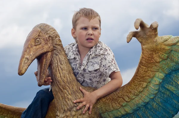 Маленький храбрый мальчик на динозавре в парке — стоковое фото