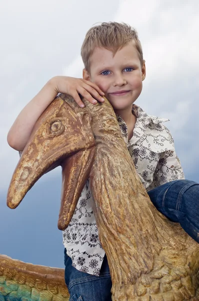 Piccolo ragazzo coraggioso su un dinosauro in un parco — Foto Stock
