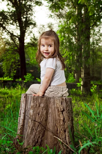 Zabawne dziewczynka siedzi na konopi — Zdjęcie stockowe