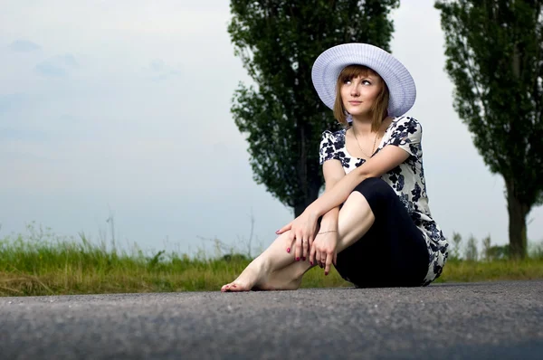 Schöne junge Mädchen sitzt in einem Hut im Freien — Stockfoto