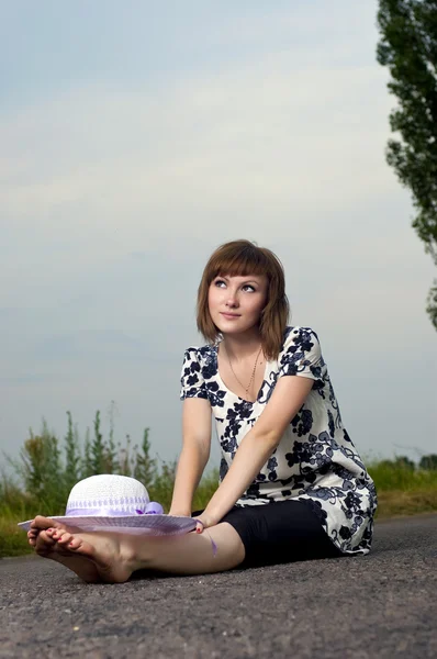 Krásná mladá dívka sedí v klobouku venku — Stock fotografie