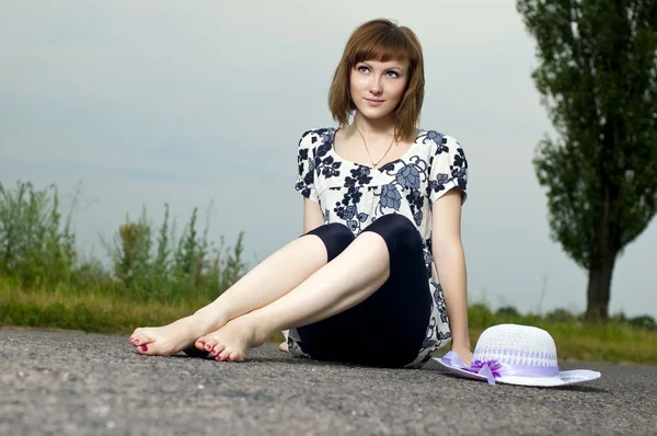 Menina bonita senta-se em um chapéu ao ar livre — Fotografia de Stock