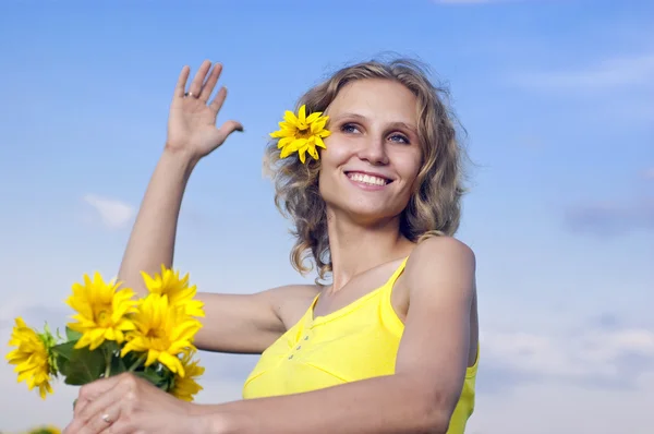 Güzel genç kız ile ayçiçeği arka plan bulutlar üzerinde — Stok fotoğraf