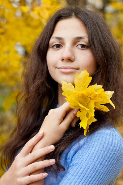 stock image Beautiful young girl is by an autumn day with yellow maple leave