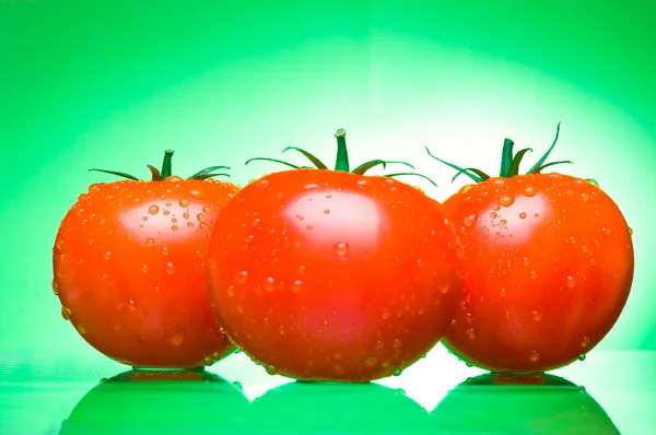 Τρεις ζουμερές ντομάτες σε πράσινο φόντο — Φωτογραφία Αρχείου