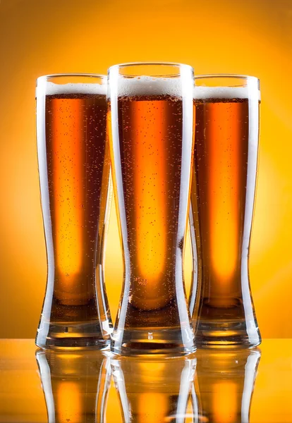 Três copos de cerveja sobre fundo amarelo — Fotografia de Stock