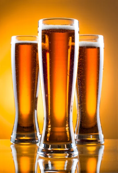 Trzy szklanki piwa na żółtym tle — Zdjęcie stockowe