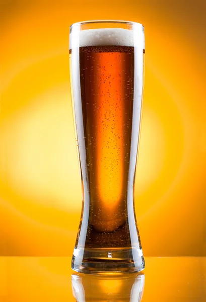 Sarı arka planda bir bardak bira. — Stok fotoğraf
