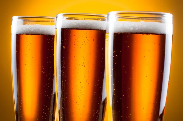 Täydellinen jäähdytetty olut keltaisella taustalla — kuvapankkivalokuva