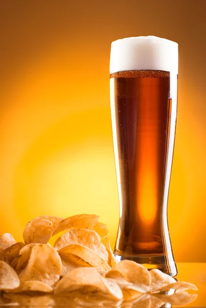 Single glass of beer and potato chips on a yellow background — Stock Photo, Image