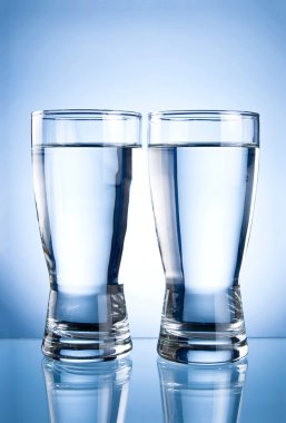 Two glasses of water on a blue background clipart