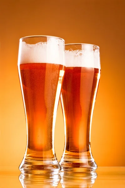 Dvě sklenice piva nad žlutým pozadím — Stock fotografie
