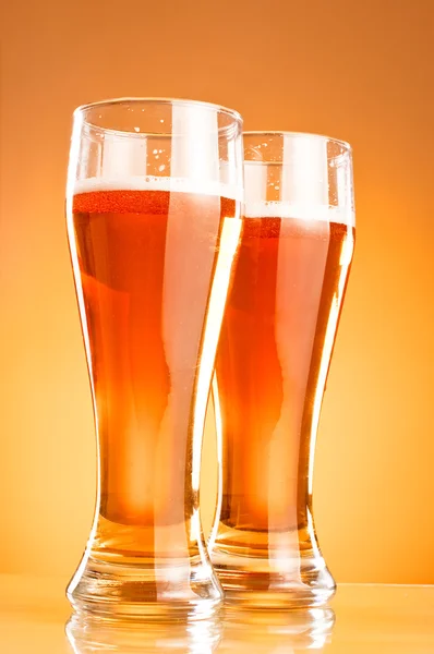 Dvě sklenice piva nad žlutým pozadím — Stock fotografie