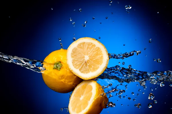Fresh lemon and two halves in the splashes of water on a dark bl — Stock Photo, Image