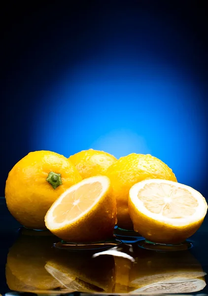 Fresh whole lemons and halves with a reflection in water on a na — Stock Photo, Image