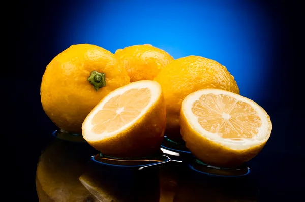 Свежие целые лимоны и половинки с отражением в воде на — стоковое фото
