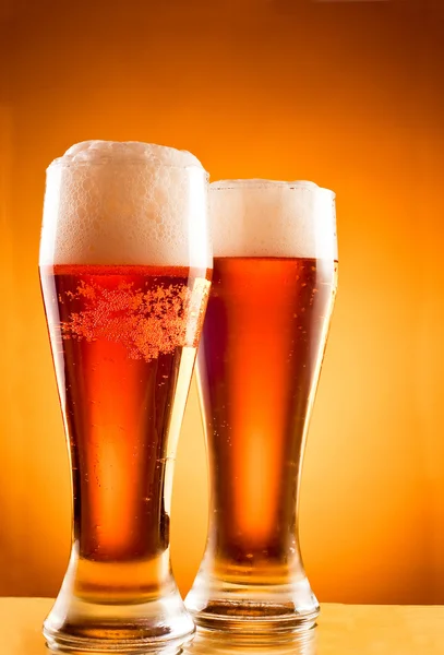 Twee glazen met koud biertje op gele achtergrond — Stockfoto