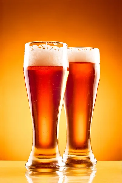Due bicchieri con birra fredda su sfondo giallo — Foto Stock