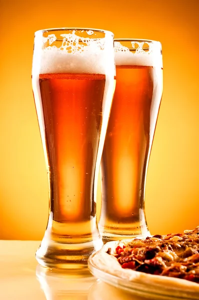 Dois copos de cerveja e pizza sobre fundo amarelo — Fotografia de Stock