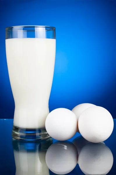 Glass of milk and three eggs on a dark blue background — Stock Photo, Image