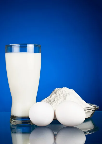 Fresh eggs, flour and milk on a dark blue background — Stock Photo, Image