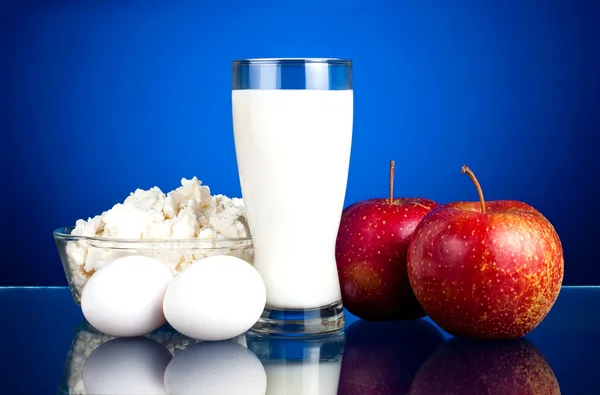 Two juicy red apples, fresh eggs and dairy products: curd and mi — Stock Photo, Image