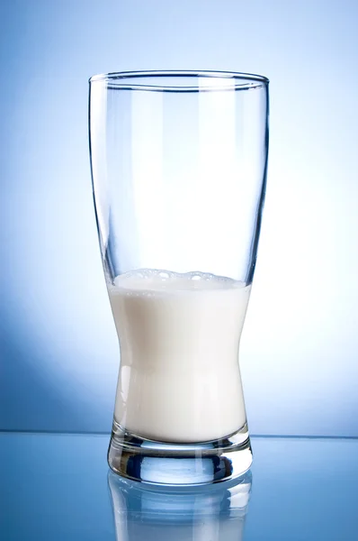 Mezzo bicchiere di latte su sfondo blu — Foto Stock