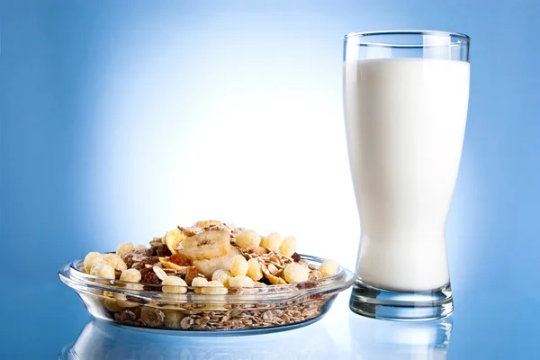 Dish of muesli and glass of fresh milk on a blue background — Stock Photo, Image