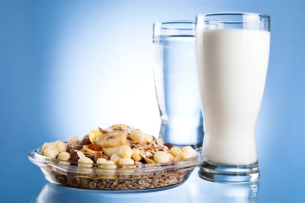 Dish of muesli, glass of fresh milk and glass of water on a blue — Stock Photo, Image