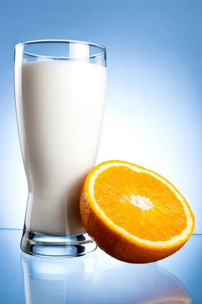 신선한 우유의 유리 및 파란 backgroun에 수 분이 많은 오렌지의 절반 — 스톡 사진