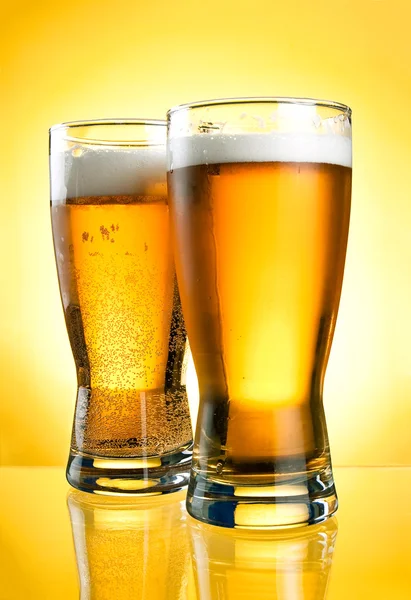 Dois copos de cerveja close-up com espuma sobre fundo amarelo — Fotografia de Stock