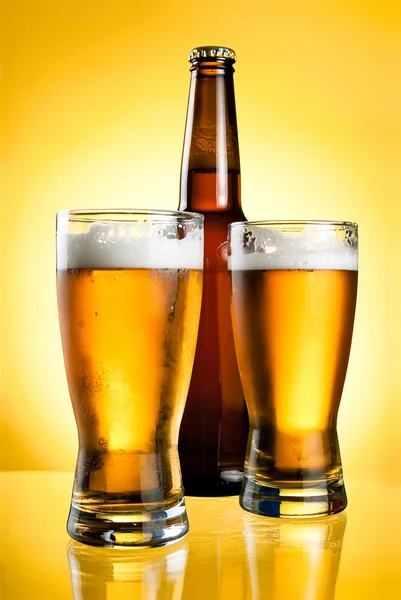 两个眼镜和黄色背景上新鲜淡啤酒瓶 — 图库照片