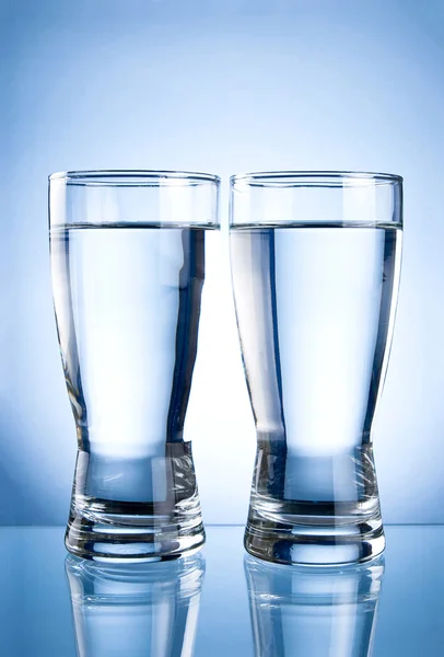 Dois copos de água em um fundo azul — Fotografia de Stock