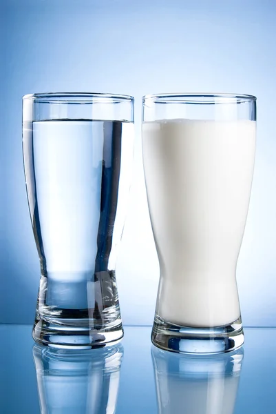 Vaso de agua y leche sobre fondo azul —  Fotos de Stock